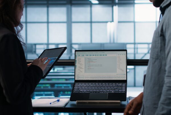 Programmers using AI technology on laptop and tablet in data center employing machine learning models. Devices used by artificial intelligence IT experts in server farm, camera A